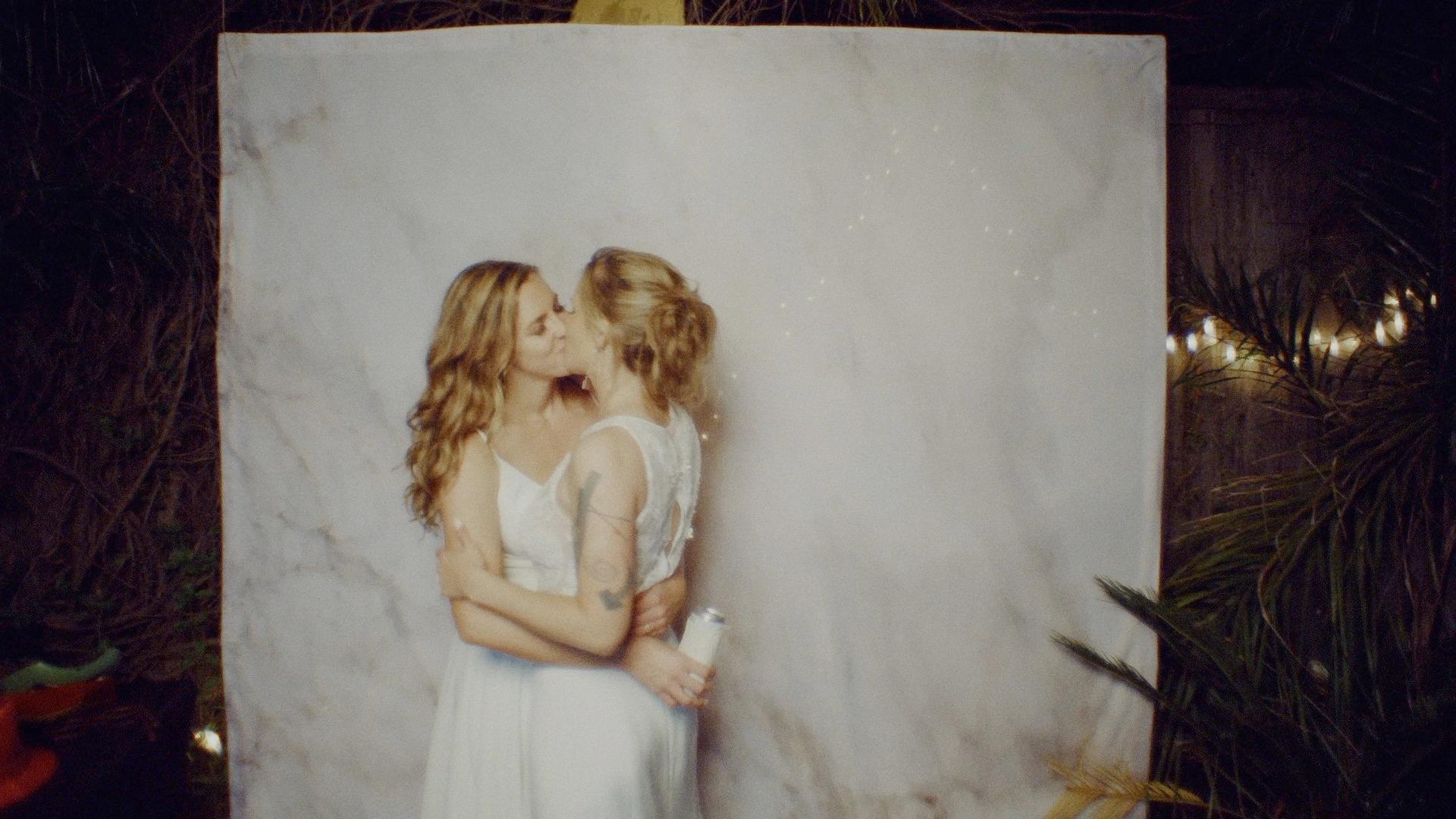 two brides kissing in front of a backdrop