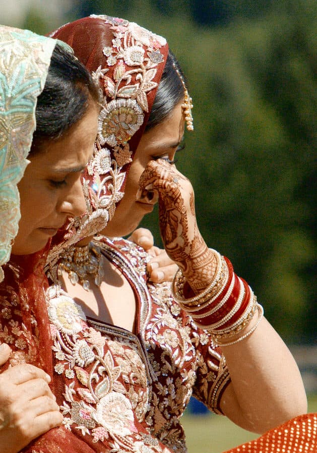 mother hugging crying daughter during sikh wedding ceremony
