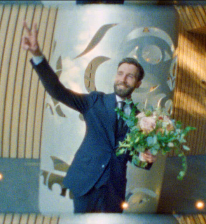 groom flashing peace sign while captured on super 8mm film