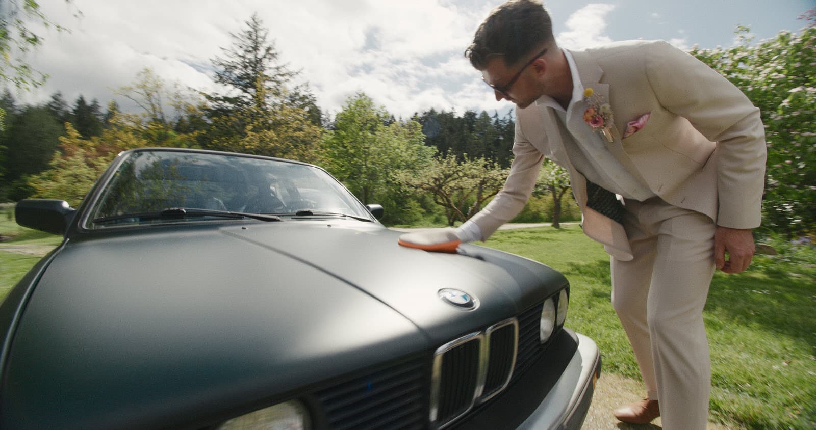 groom cleaning green bmw on wedding day