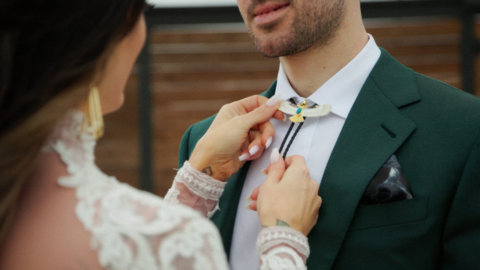 bride helping groom put on bolo tie